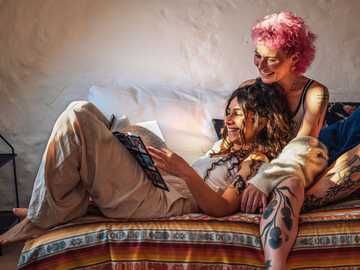 Zwei Frauen lesen ein Buch auf dem Sofa